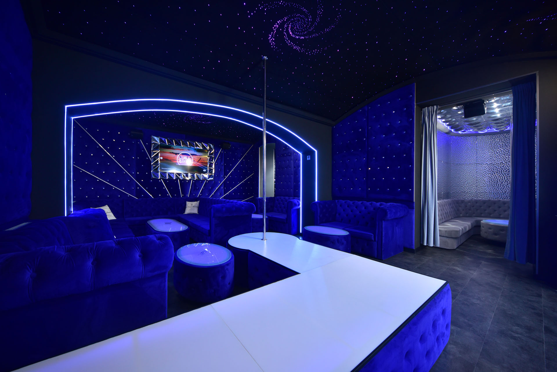 Interiér Blue Funny — modré neonové oblouky, hvězdný strop a chesterfield gauče
